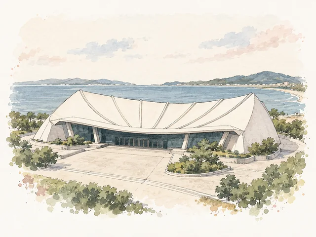 扇形米白色弧頂建築前面係淺色空地同綠色植物。